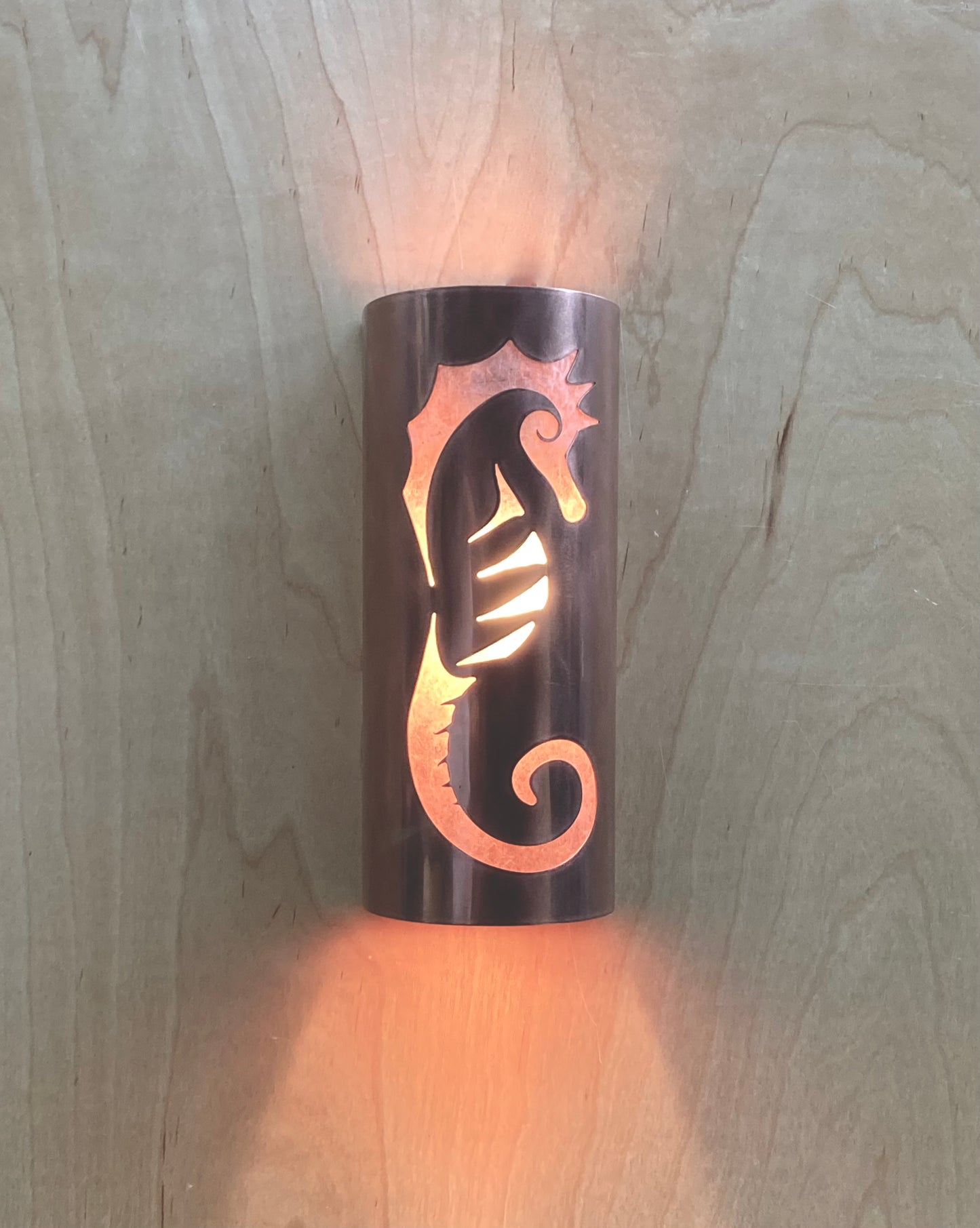 Copper sconce light in a half round shape with a seahorse design cut out