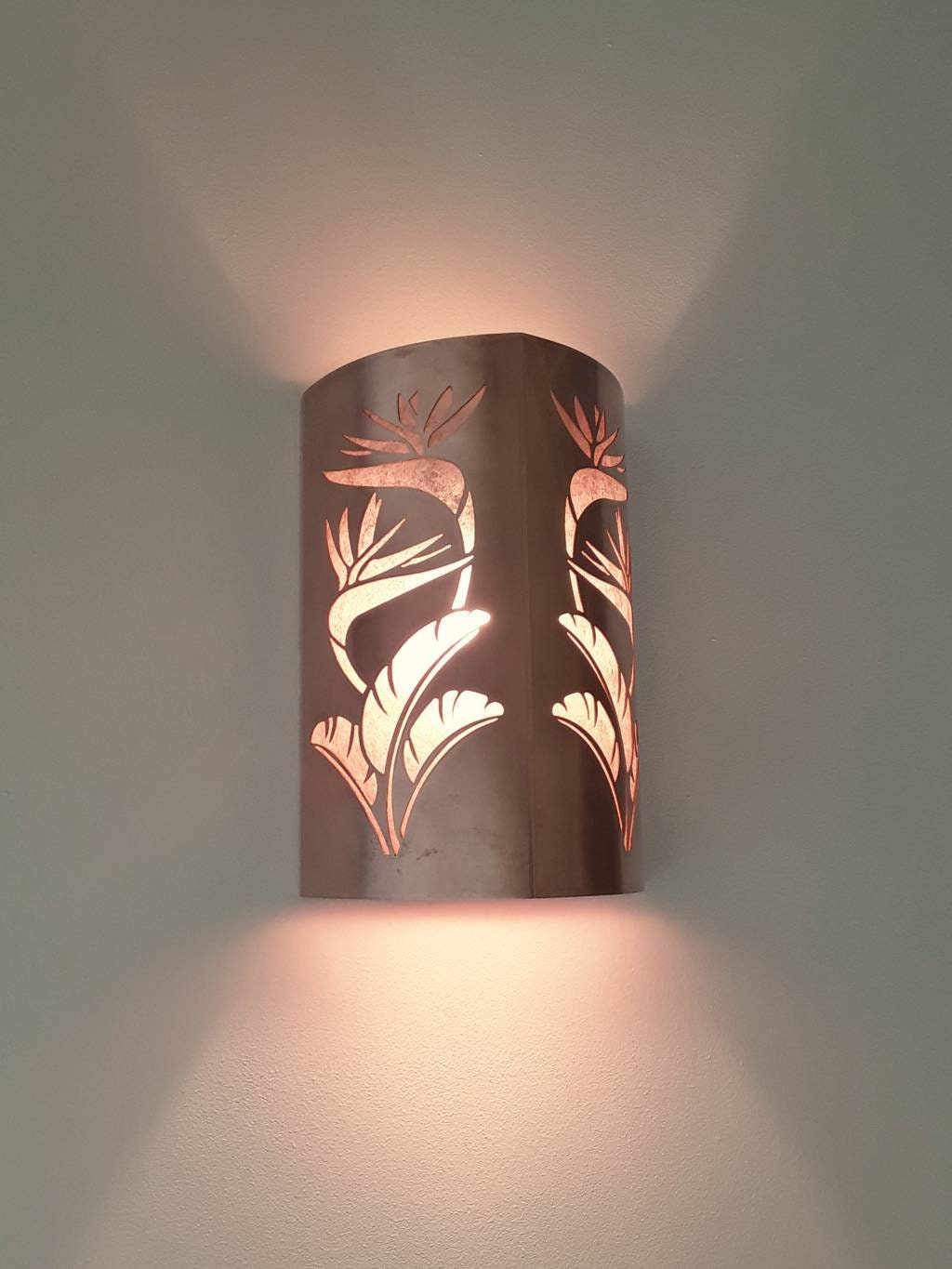 side view of a copper sconce light with bird of paradise design